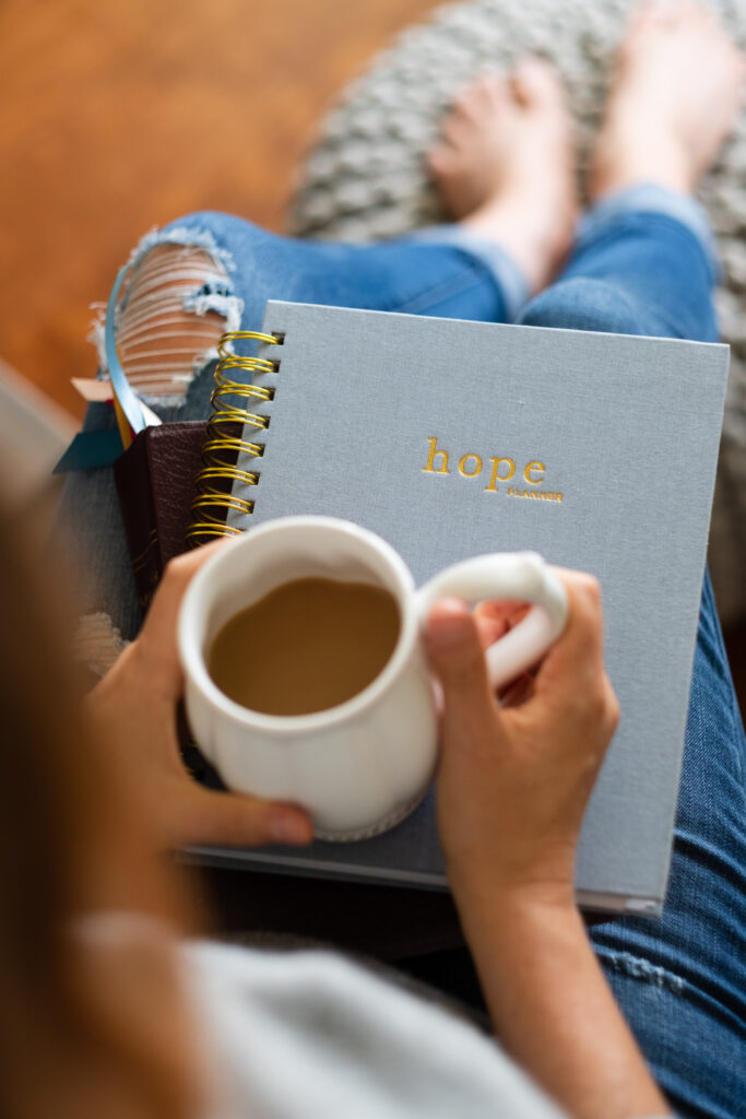 Christian woman drinking coffee with The Hope Planner on her lap