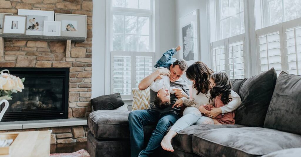 Christian family snuggling and laughing on the couch as they build family intimacy