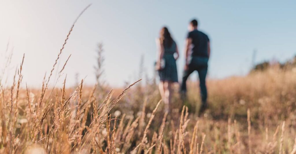 blurred couple walking through a field of wheat