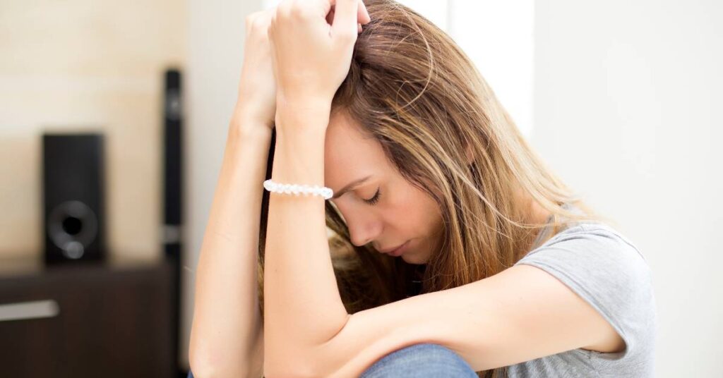 sad woman with her arms on her head, struggling with the impact of depression in her life