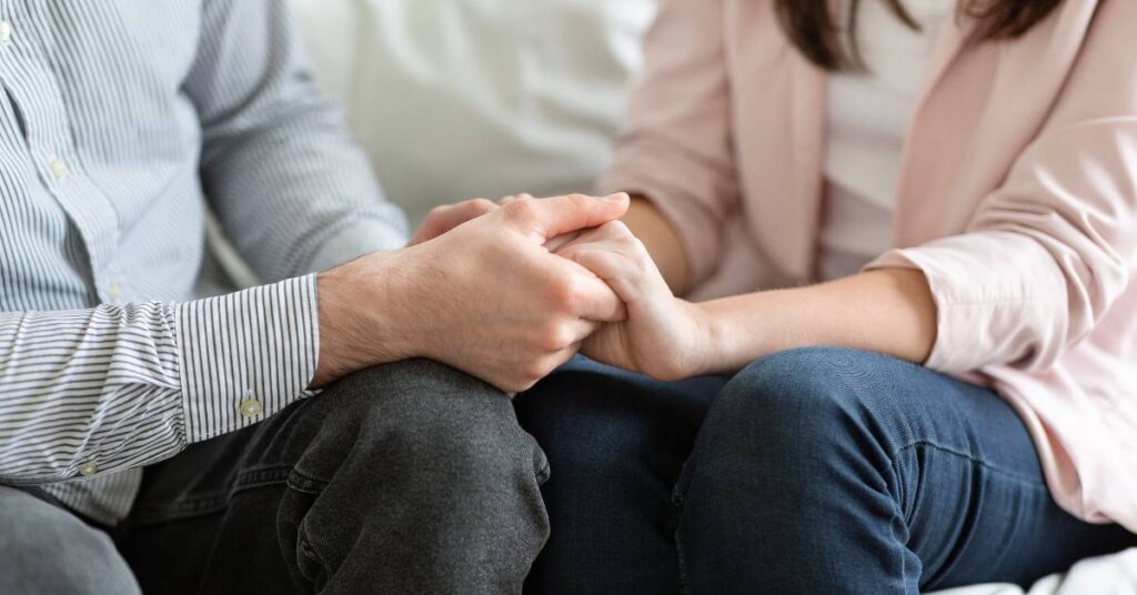 close up photo of a couple holding hands, as they talk together through marriage communication problems