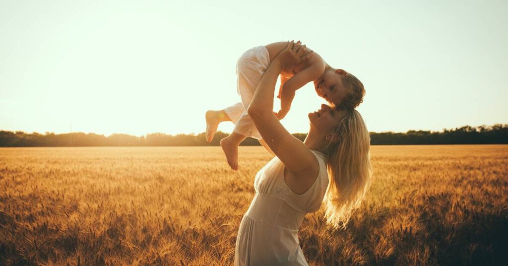 Christian mom holding her son up and touching foreheads with a beautiful background of golden wheat