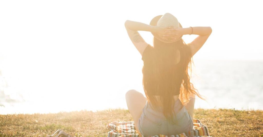 woman looking away from the camera out over the ocean enjoying a heart of gratitude and beautiful fall day