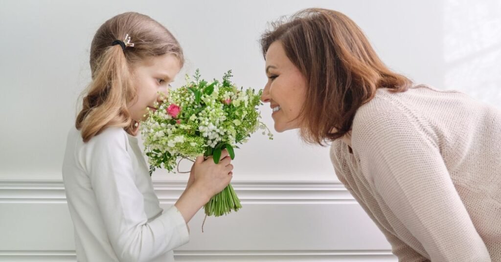 photo of Christian parenting as a mom smiles and smells the flowers her daughter is holding.